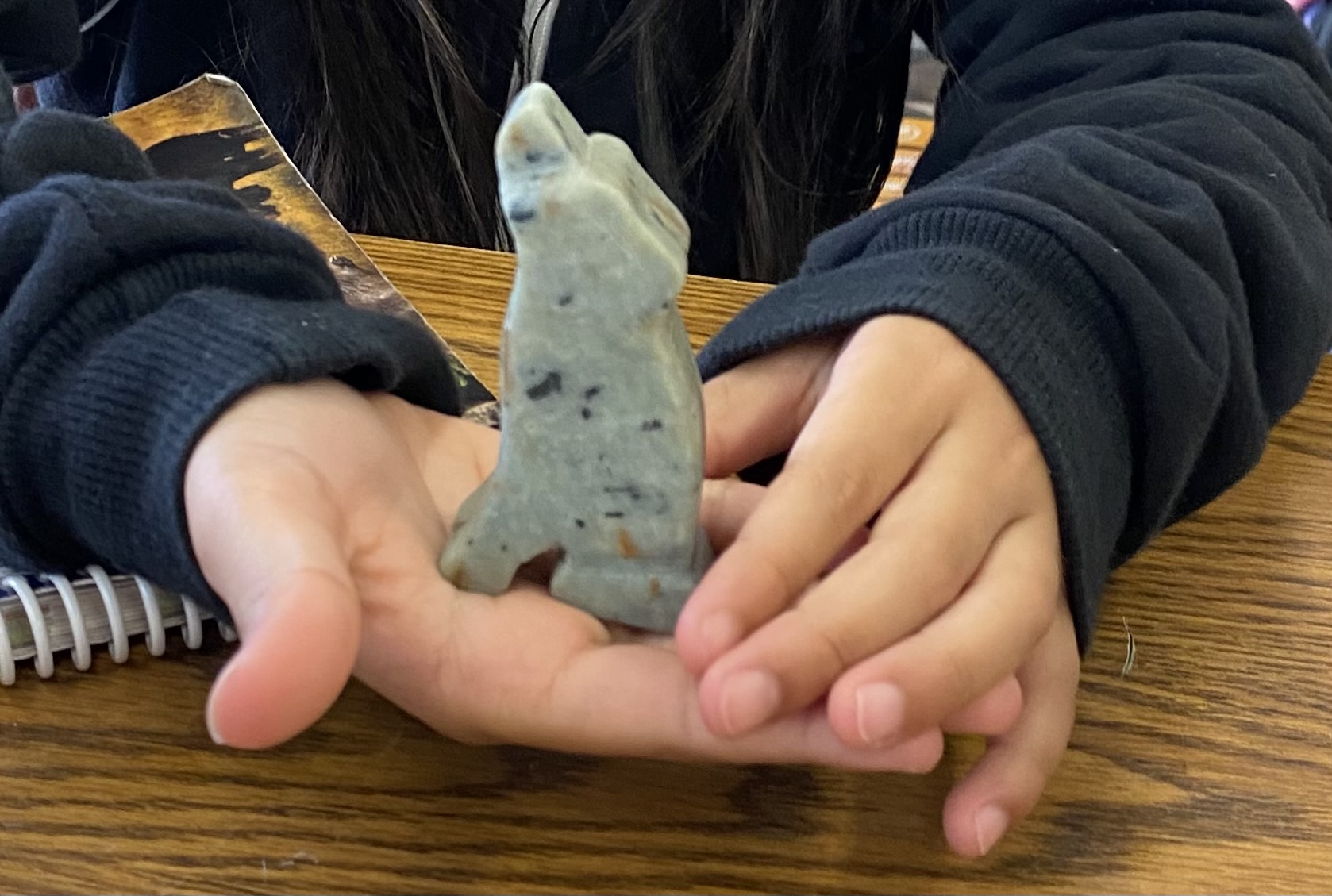 Child holding a soapstone carving of a wolf