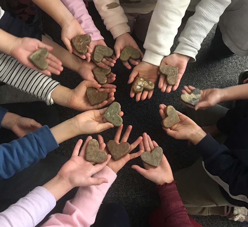 A group of children holding a carvings of soapstone hearts
