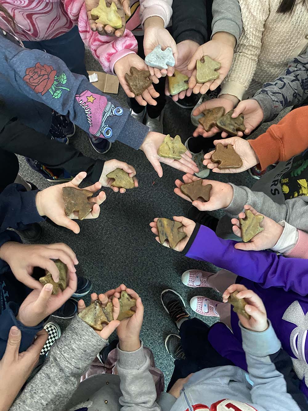 A group of children holding carvings of soapstone shapes